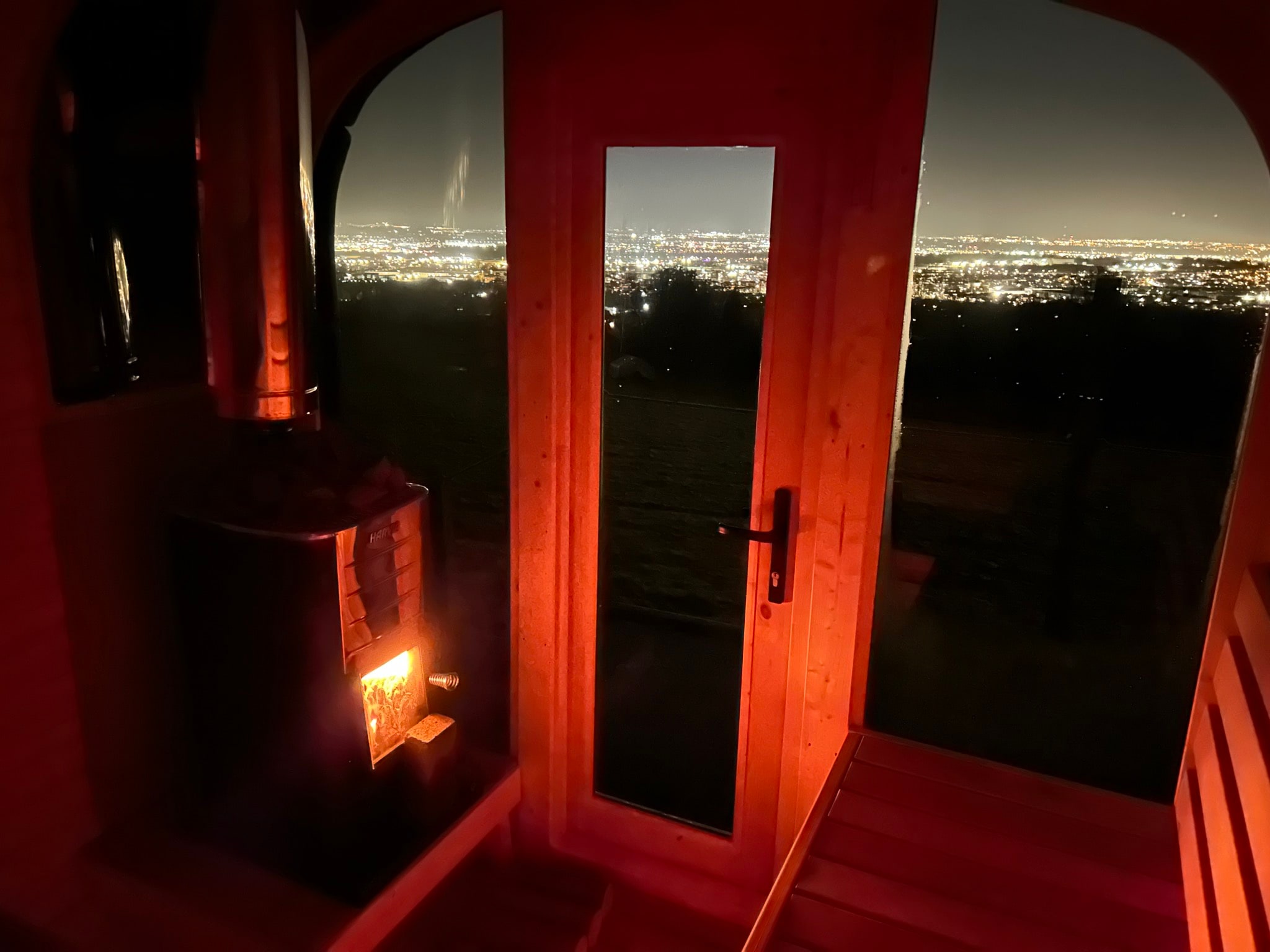 Warm wood-fired sauna interior overlooking Dublin at night